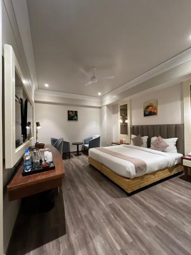 a hotel room with a large bed and a desk at Hotel Apricia in Ludhiana