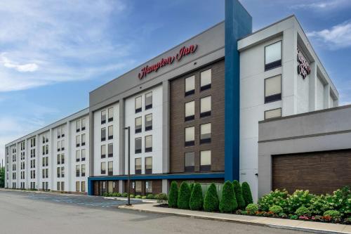 a large white building with a red sign on it at Hampton Inn Woodbridge in Woodbridge