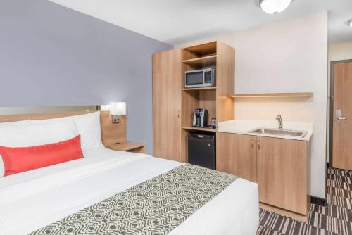 a hotel room with a bed and a sink at Microtel Inn & Suites by Wyndham Sudbury in Sudbury