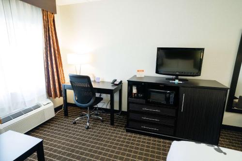 a hotel room with a desk and a tv and a room at Sleep Inn & Suites West Knoxville in Knoxville