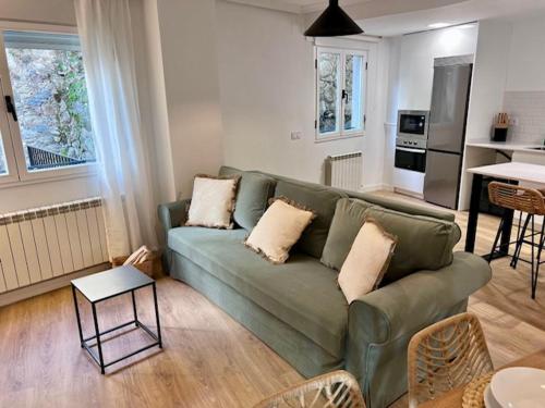 a living room with a green couch and a kitchen at Villa de Béjar in Béjar