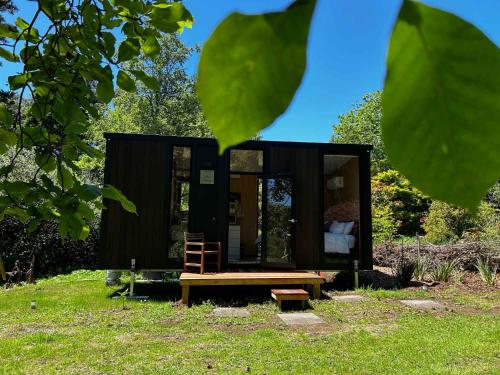 a tiny house with a bench in the grass at Kereru Creek by Tiny Away in Tataraimaka