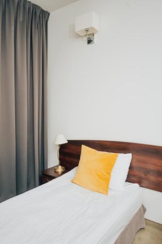 a bedroom with a bed with a yellow pillow at Hotel Sphinx in Żabia Wola