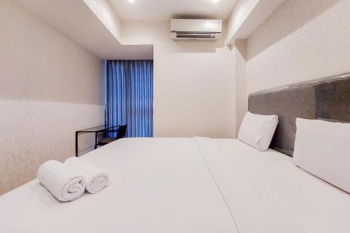 a bedroom with a white bed with towels on it at Homey and Tranquil 1BR Branz BSD City Apartment By Travelio in Tangerang