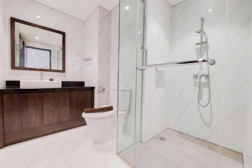 a bathroom with a shower and a toilet and a sink at Homey and Tranquil 1BR Branz BSD City Apartment By Travelio in Tangerang