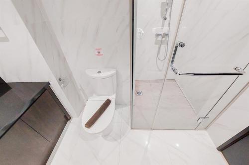 a white bathroom with a shower and a toilet at Homey and Tranquil 1BR Branz BSD City Apartment By Travelio in Tangerang