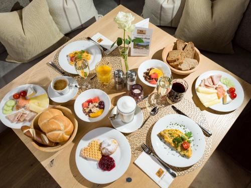 Una mesa con platos de comida para desayunar. en Hotel Waldfriede - Der Logenplatz im Zillertal, en Fügen
