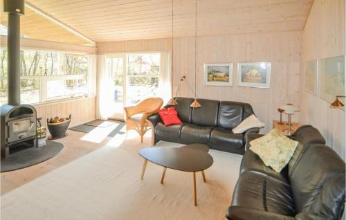a living room with a leather couch and a fireplace at Holiday Home Kalvehavestien Glesborg Iii in Fjellerup Strand