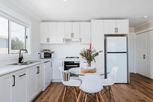 a kitchen with white cabinets and a table and chairs at Joseph's Place - A Restful Retreat for Two in Mudgee