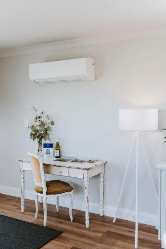 a white desk with a chair and a table with a plant at Joseph's Place - A Restful Retreat for Two in Mudgee