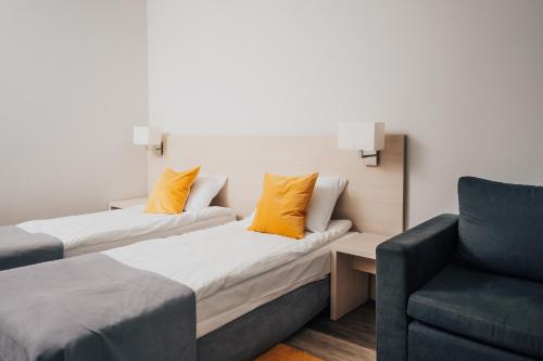 two beds in a room with a couch and a chair at Hotel Sphinx in Żabia Wola