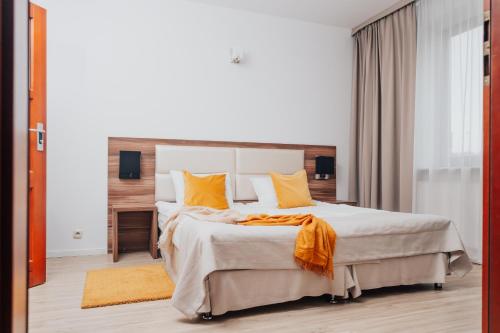 a bedroom with a large bed with orange pillows at Hotel Sphinx in Żabia Wola