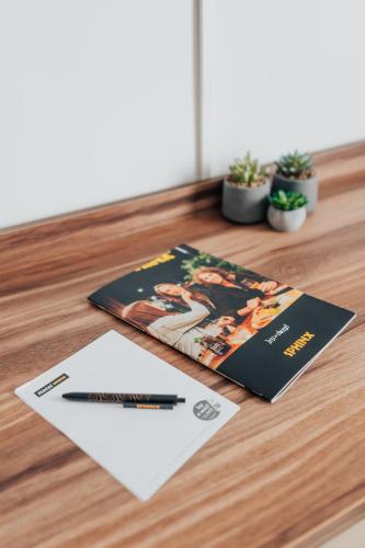 a book and a pen on a wooden table at Hotel Sphinx in Żabia Wola