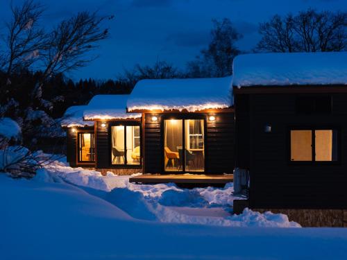 a house covered in snow at night with lights at Myoko Onsen cottage Ajisai in Myoko