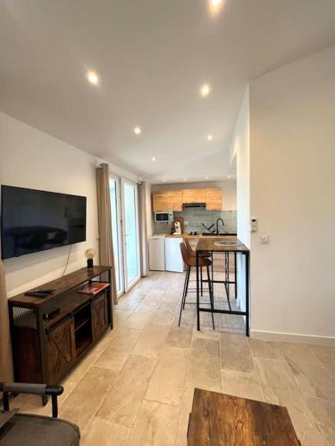 un salon avec une télévision et une table ainsi qu'une cuisine dans l'établissement Superbe studio neuf vue mer, à Monticello