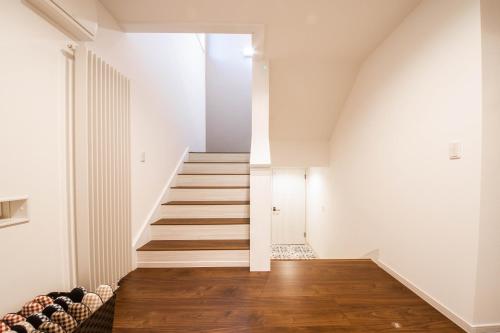 a staircase in a house with white walls and wooden floors at THE SUN LOUNGE in Kushiro