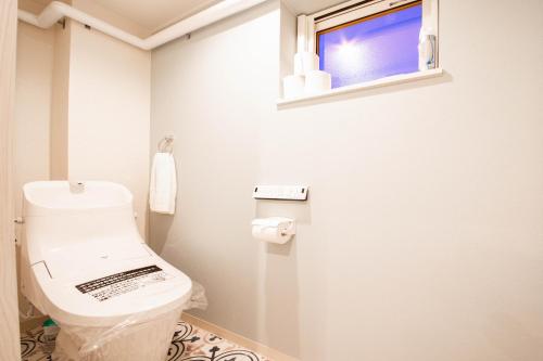 a white bathroom with a toilet and a window at THE SUN LOUNGE in Kushiro