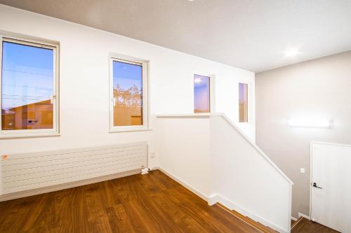 an empty room with white walls and windows at THE SUN LOUNGE in Kushiro