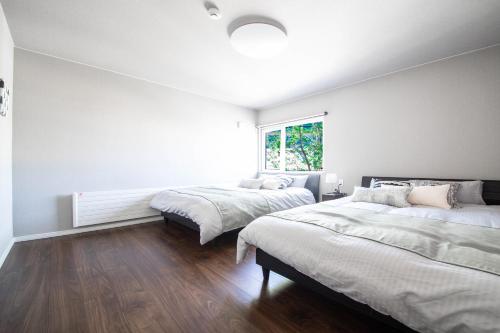 two beds in a room with white walls and wood floors at THE SUN LOUNGE in Kushiro