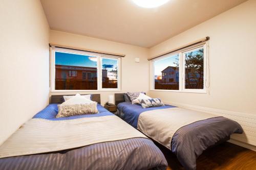two beds in a room with two windows at THE SUN LOUNGE in Kushiro