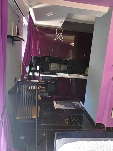cocina con armarios morados y encimera negra en Guest House CELLOSIA, en Përmet