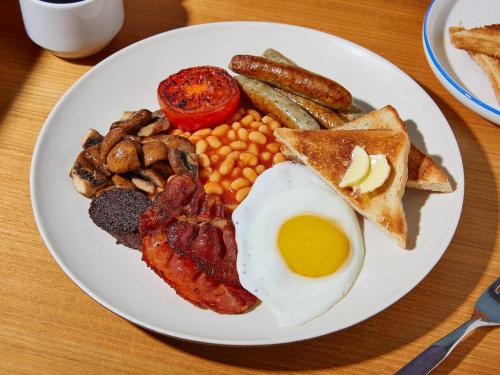 un plato de desayuno con huevos beicon y tostadas en Green House Rooms, en Mirissa