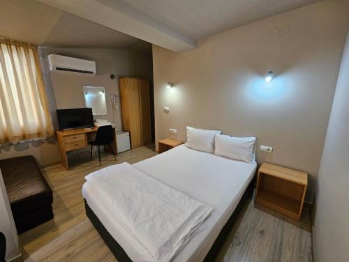 a bedroom with a bed and a desk with a television at Hotel Racic Self-Check In in Voyvodinovo