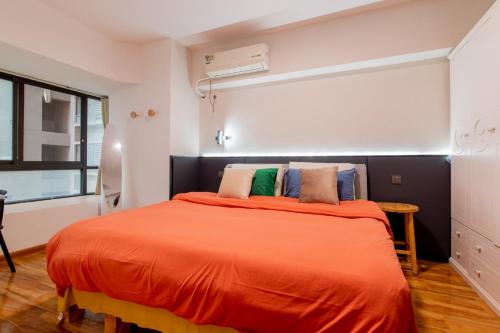 a bedroom with a bed with an orange blanket at Ban Xia Sunshine Hotel- Drum Tower & YONGNING Gate Branch in Xi'an