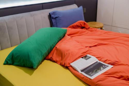 a bed with green and orange pillows and a book on it at Ban Xia Sunshine Hotel- Drum Tower & YONGNING Gate Branch in Xi'an