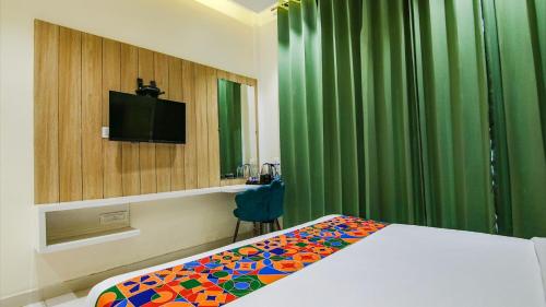 a hotel room with a bed and a television and green curtains at Hotel Global Inn in Amritsar