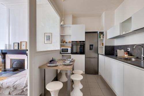 une cuisine avec des armoires blanches et une table avec des tabourets dans l'établissement Appartement au coeur de la presqu'ile, à Lyon