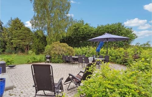 a patio with chairs and an umbrella in a garden at Cozy Apartment In Kværndrup With Wifi in Kværndrup