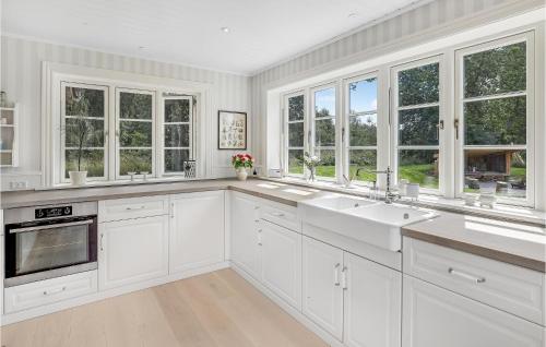 a white kitchen with two sinks and windows at Cozy Home In Aakirkeby With Kitchen in Vester Sømarken