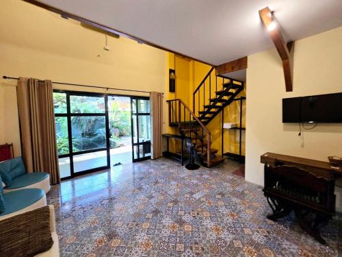 a living room with a couch and a television and a staircase at Baibon2 Homestay Thalang Phuket in Thalang