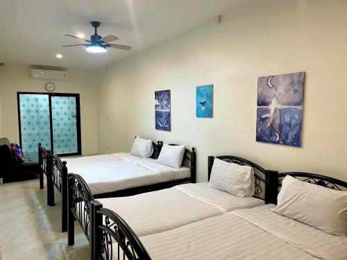 a room with three beds and a ceiling fan at PJ Hostel & Bar in Pattaya