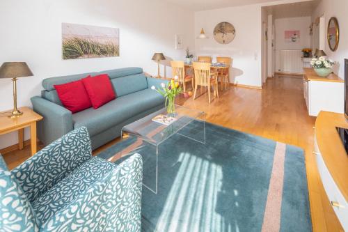 a living room with a blue couch and a glass table at Kleine Möwe 08 in Norderney
