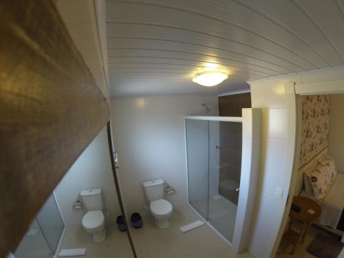 a bathroom with two toilets and a walk in shower at Pousada UpSerra in Urubici