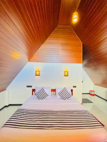 a bedroom with a large bed with a wooden ceiling at Cloudy Hill Cottage in Ella