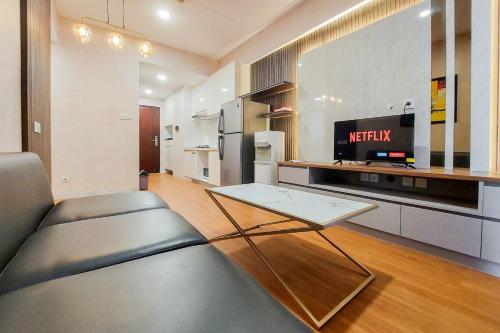 a living room with a couch and a television at Spacious and Nice 2BR at Sky House BSD Apartment By Travelio in Tangerang