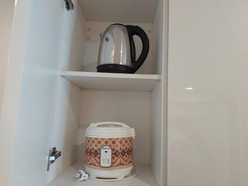 a tea kettle is sitting on a shelf in a cupboard at Spacious and Nice 2BR at Sky House BSD Apartment By Travelio in Tangerang