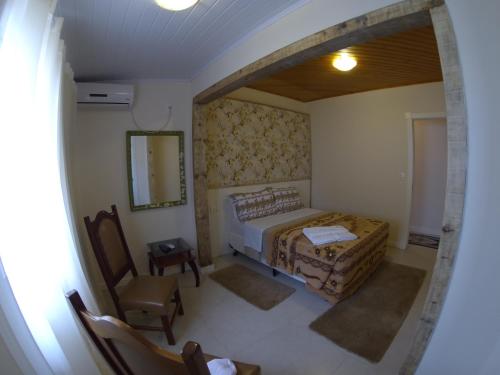 a bedroom with a bed and a chair and a mirror at Pousada UpSerra in Urubici
