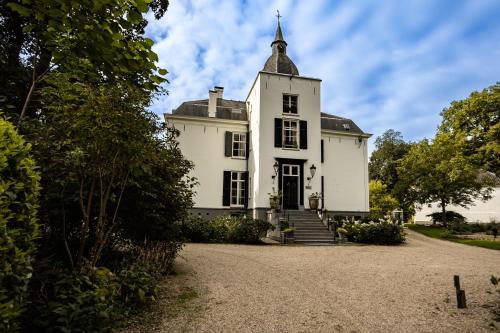an old white house with a tower on a driveway at Landgoed Loenen B&B in Slijk-Ewijk