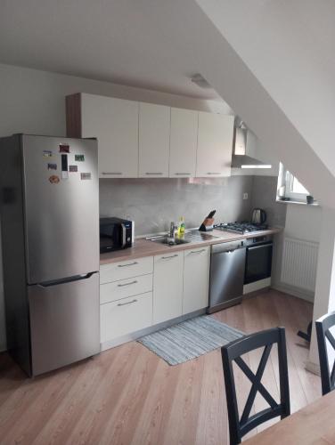 a kitchen with white cabinets and a refrigerator at Deniro Apartment in Požega