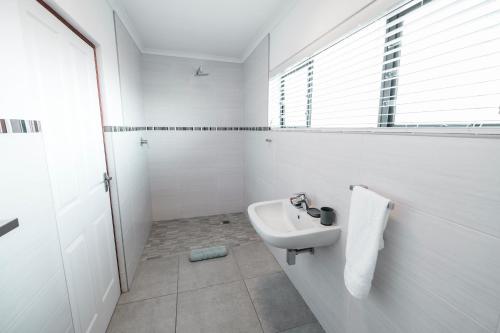 a white bathroom with a sink and a window at Hermanus Reefs in Hermanus