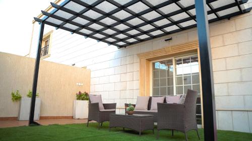 a pergola over a patio with chairs and a table at شقق بيت العز Bait Alez in Jeddah