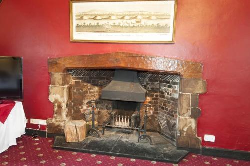 a fireplace in a room with a red wall at Roebuck Inn in Stevenage