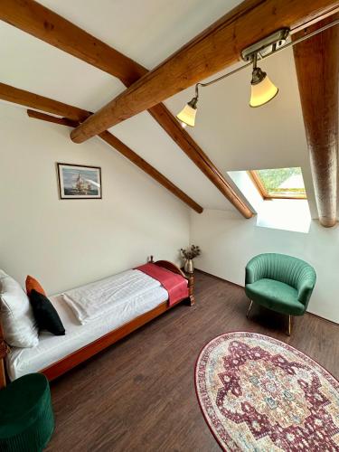 a bedroom with a bed and a green chair at Tia Maria in Győr