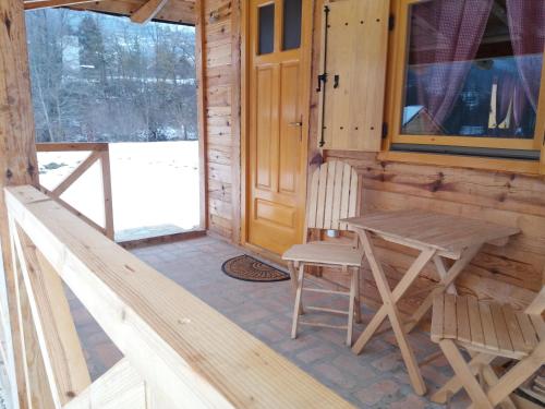 a wooden porch with a wooden chair and a table at Apartment Mateja in Mokra Gora