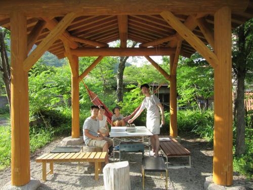three men sitting at a picnic table under a pavilion at Tsuyukusa in Takayama