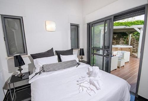 a bedroom with a white bed and a balcony at Black&White in Had Nes